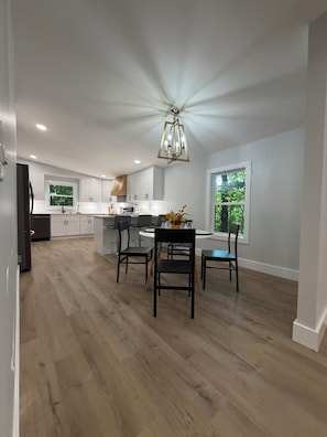 A spacious kitchen with white cabinets, a central island, and a dining area with chairs.