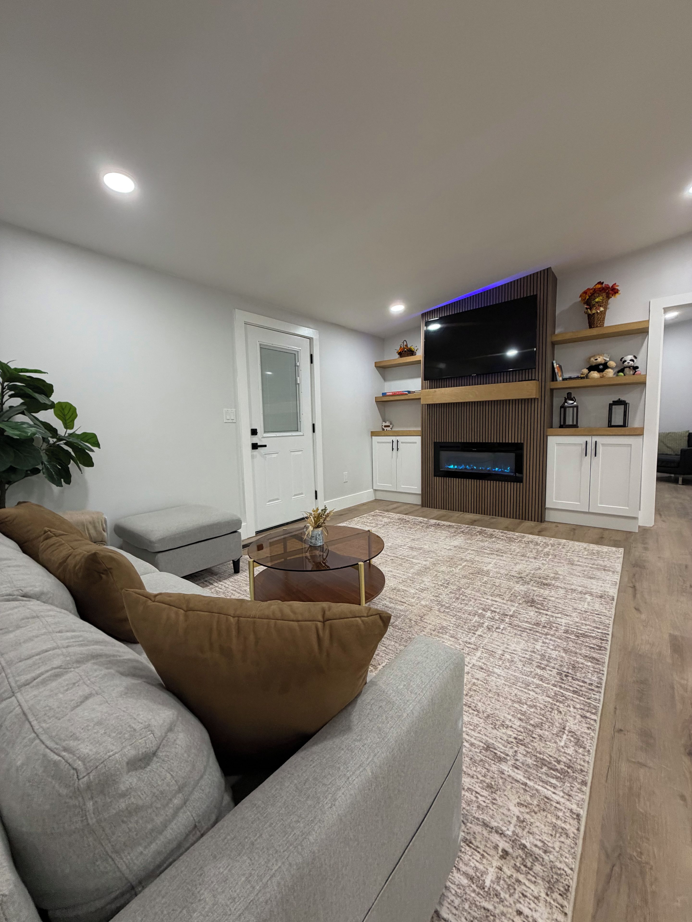 Ein modernes Wohnzimmer mit einer Couch, Couchtisch, Fernseher und einer integrierten Unterhaltungseinheit.
