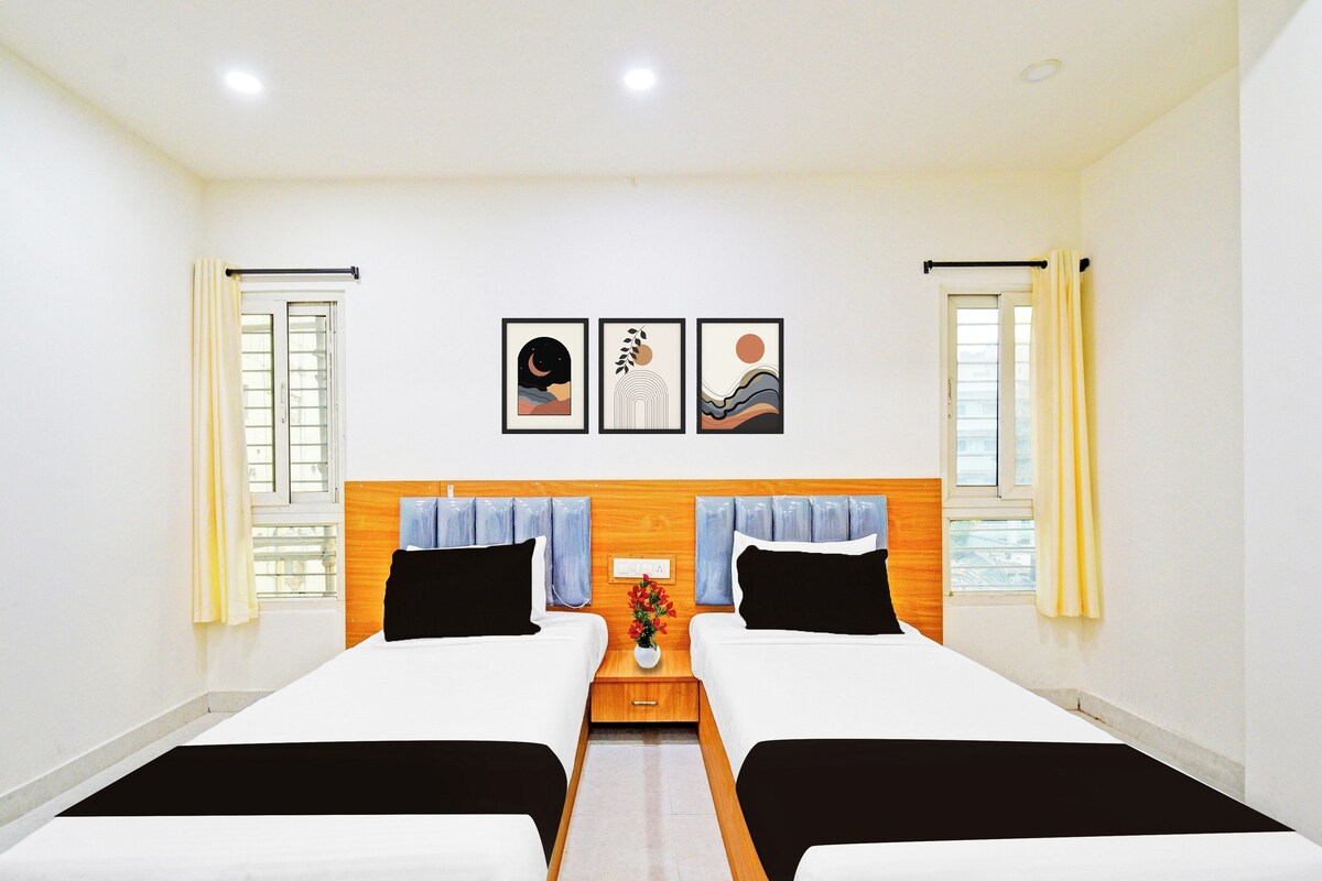 Habitación de hotel con dos camas, cabecero de madera, mesita de noche y tres cuadros en la pared.