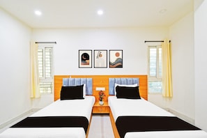 Habitación de hotel con dos camas, cabecero de madera, mesita de noche y tres cuadros en la pared.