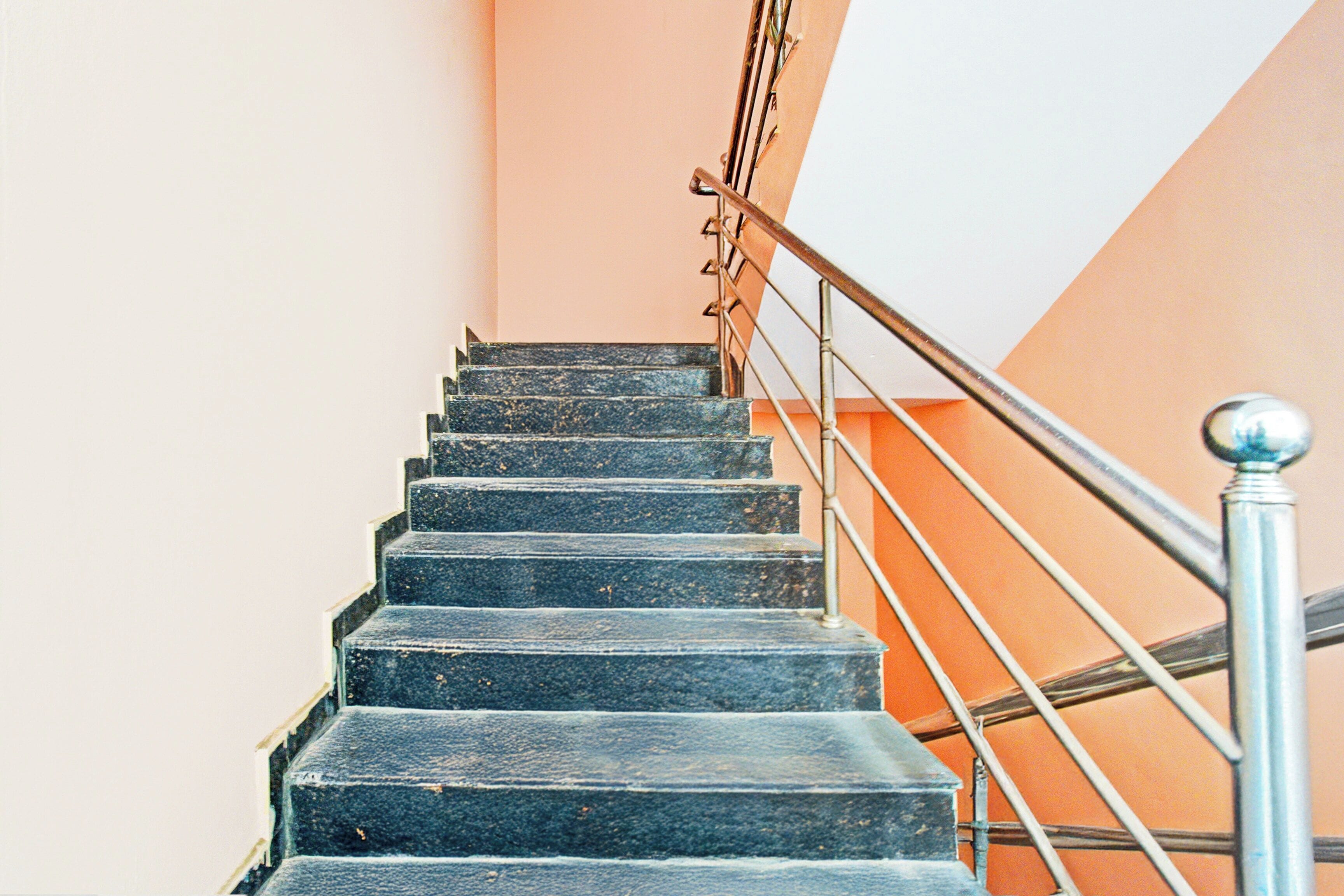 Un escalier avec des rampes et une main courante en métal, qui monte.