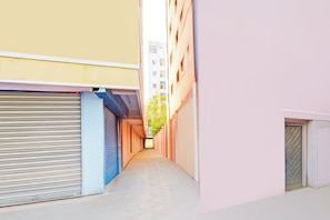 A narrow alleyway between buildings with closed shutters on the left and a tree in the distance. - Townhouse OAK Santosh Nagar Hyderabad (Hyderabad)