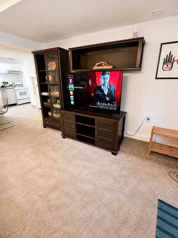 A living room with a flat-screen TV mounted on a wooden entertainment unit.