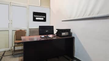 Um espaço de escritório pequeno com uma mesa, uma cadeira, uma impressora e uma placa indicando que o ambiente é exclusivo para uso da empresa.