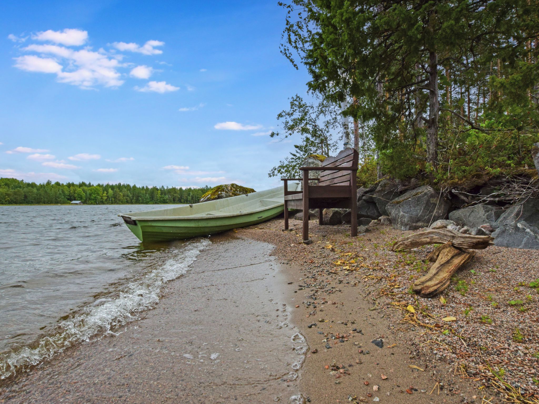 Un lac paisible, avec un bateau vert amarré à un banc en bois sur la rive.