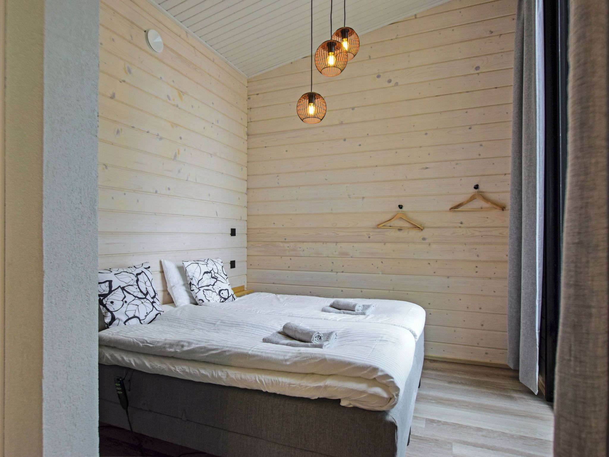 Une chambre à coucher avec un lit, des luminaires suspendus et un mur en bois.