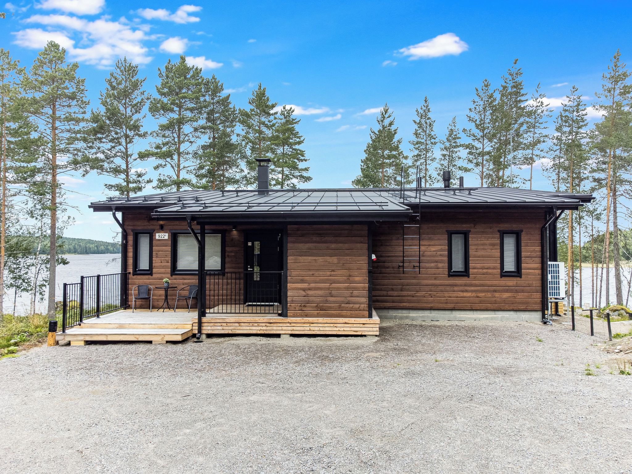 Une cabane avec une façade en bois, un porche à l’avant et une allée gravillonnée.
