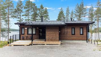 Une cabane avec une façade en bois, un porche à l’avant et une allée gravillonnée.