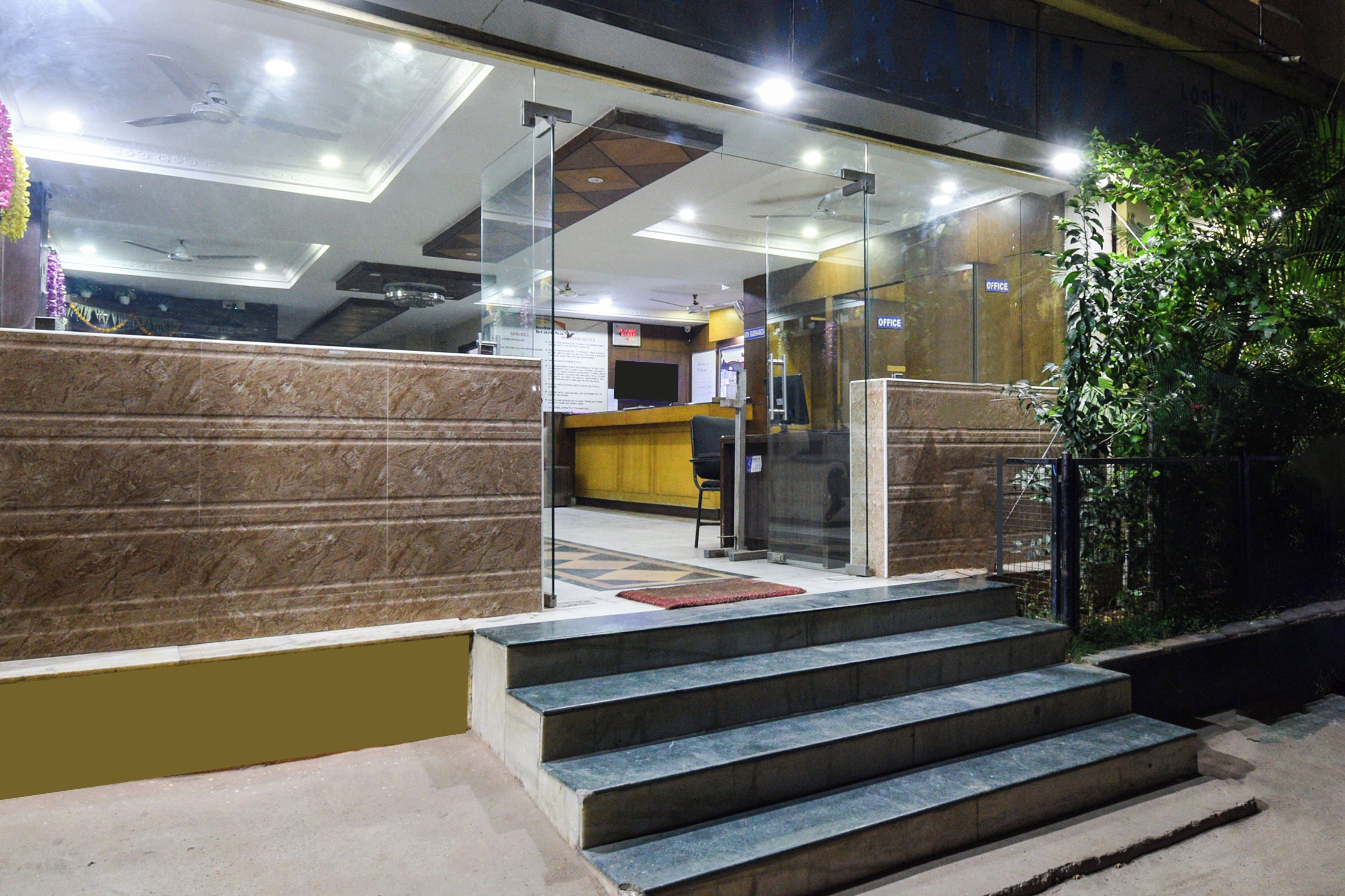 A hotel lobby with a reception desk, a staircase leading to an upper floor, and a glass partition.