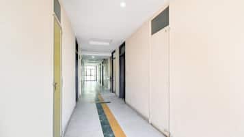 Un long couloir étroit, avec des portes de chaque côté, qui mène à une pièce lumineuse au bout.