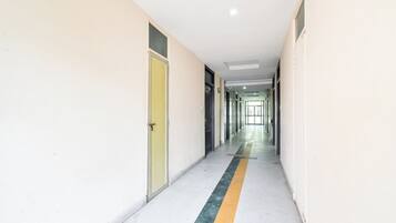 A long, narrow hallway with doors on both sides, a yellow stripe on the floor, and a ceiling light.
