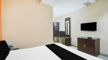 Une chambre d’hôtel avec un lit, un bureau, un miroir et une télévision.