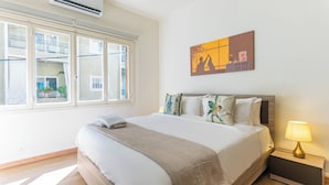 A hotel room with a bed, a nightstand, a lamp, a window, and a wall art piece. - Rue - 2-BR Apt. & Balcony in Mar Mikhael (Beirut)