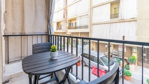 A balcony with a round table and chairs, a potted plant, and a view of a multi-story building with balconies. - Rue - 2-BR Apt. & Balcony in Mar Mikhael (Beirut)