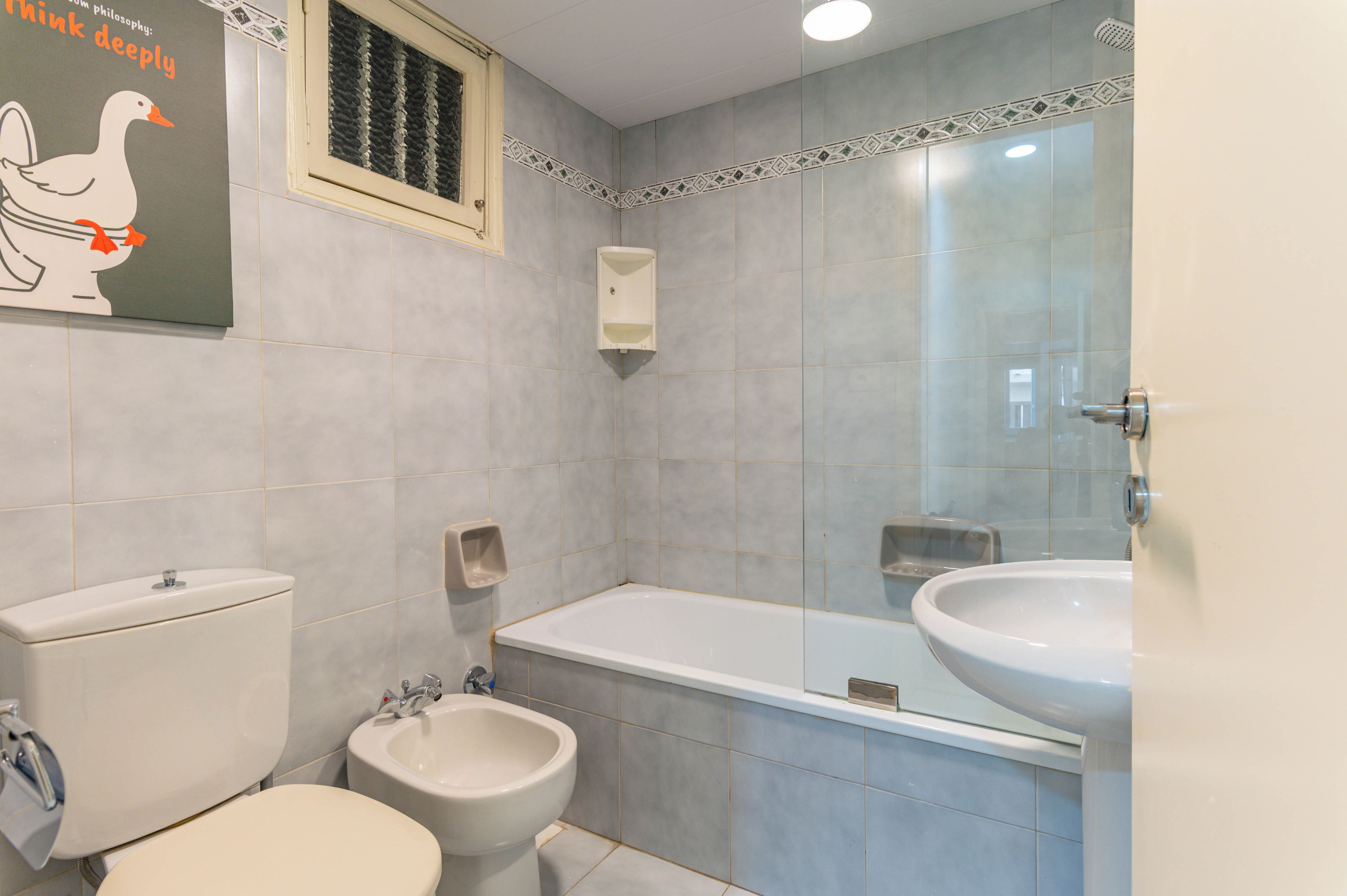 A bathroom with a toilet, bidet, bathtub, and a large mirror.