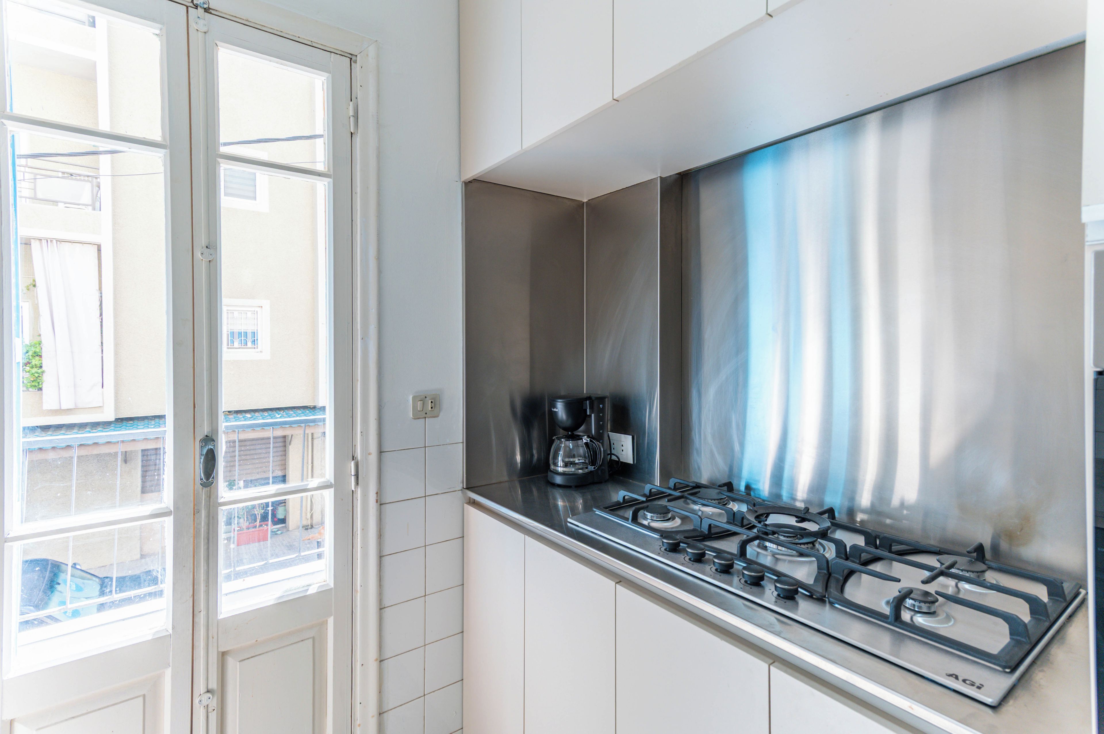 A kitchen with a gas stove, a coffee maker, and a window with a view of the outside.