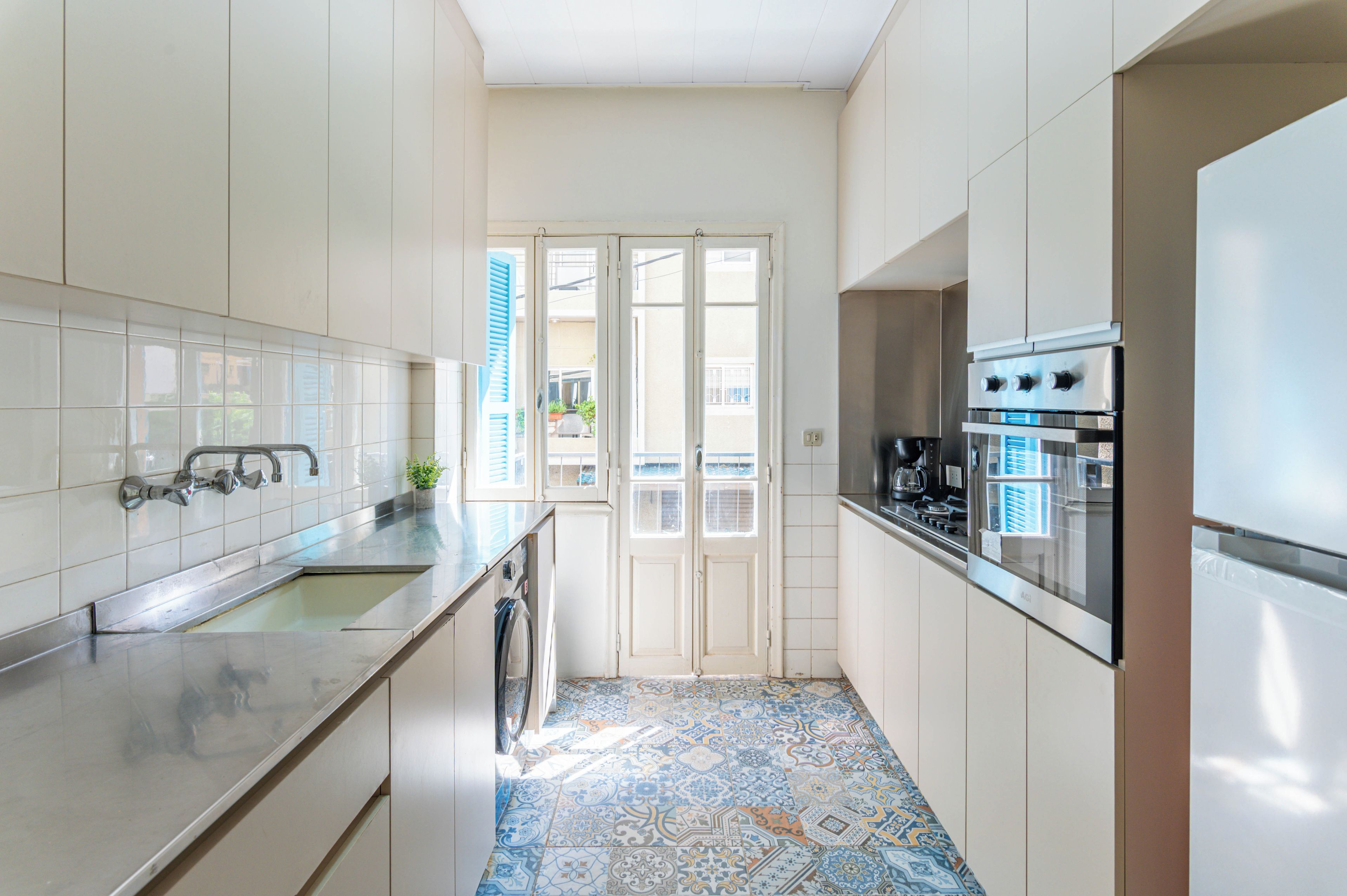 A compact kitchen with a built-in oven, a washing machine, and a sink.
