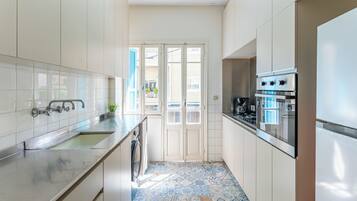 A compact kitchen with a built-in oven, a washing machine, and a sink.