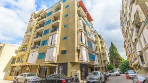 A multi-story residential building with balconies, parked cars, and a clear sky. - Rue - 2-BR Apt. & Balcony in Mar Mikhael (Beirut)