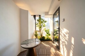 Un interior moderno con una mesa de mármol, suelo con dibujo de espiga y vistas a la vegetación a través de un ventanal.