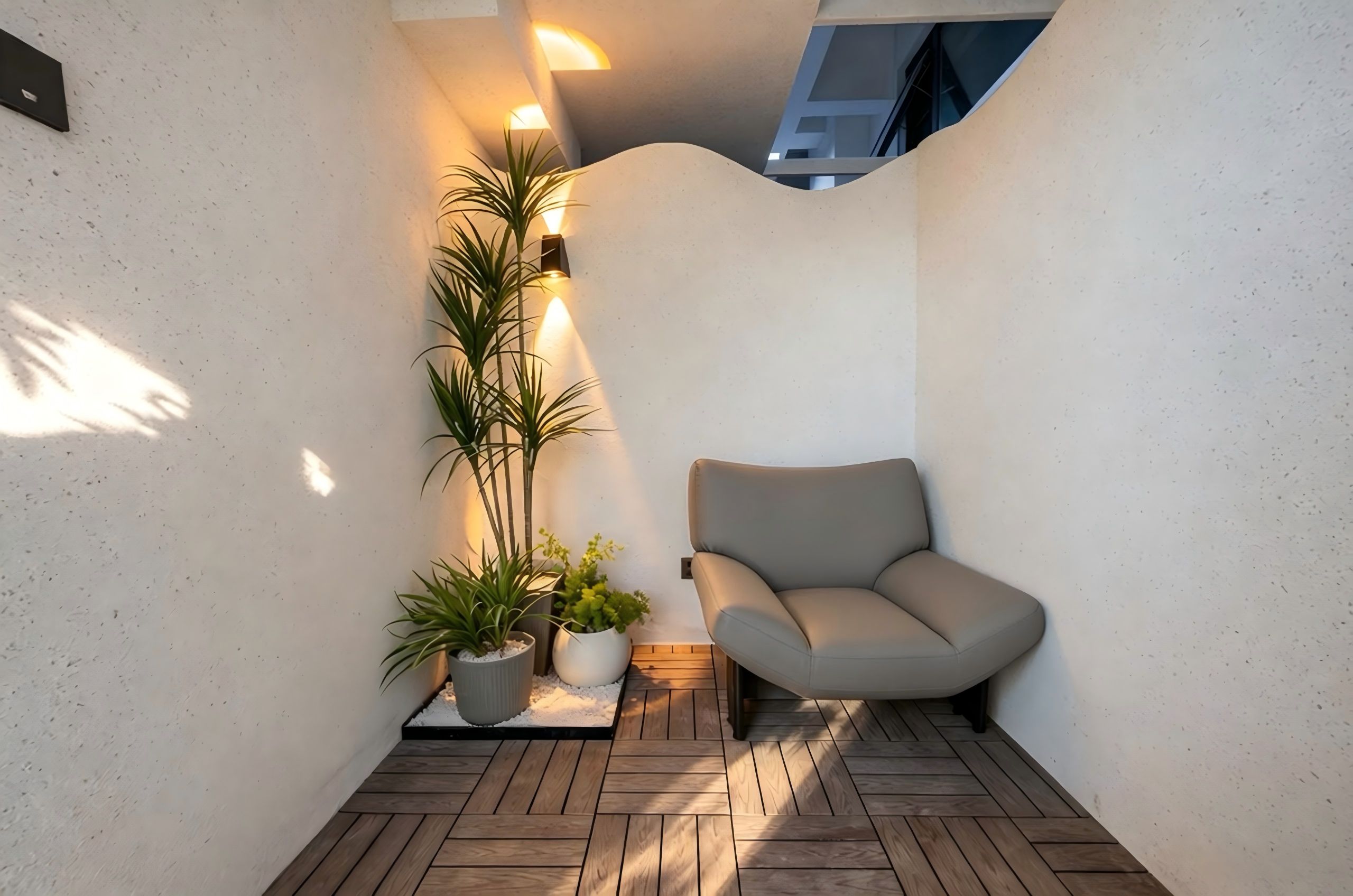 A corner room with a cushioned seating area, a potted plant arrangement, and a wooden floor.
