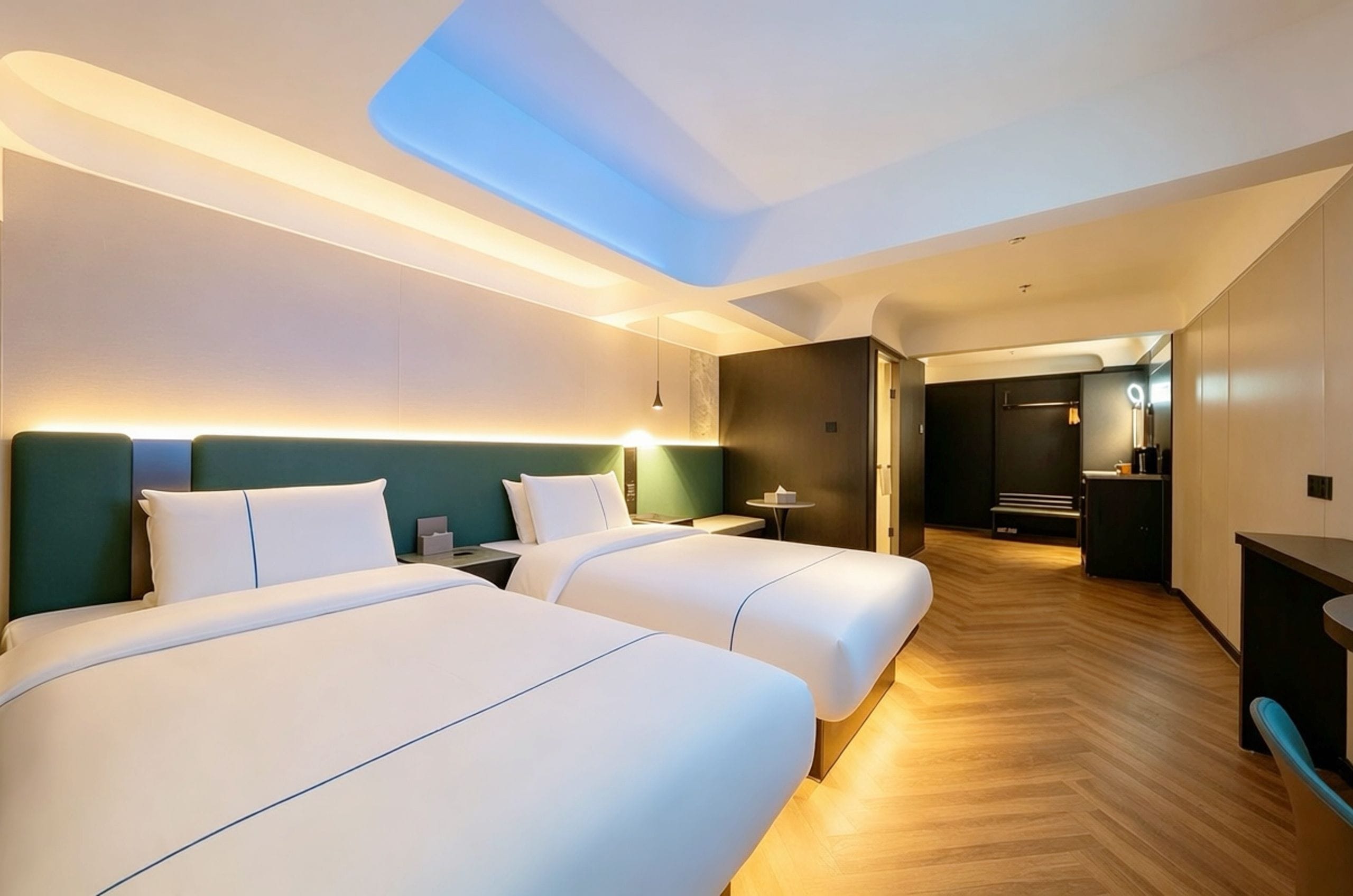 A hotel room with two beds, a skylight, a desk, and a bathroom visible through an open door.