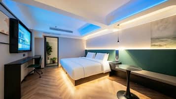 A modern hotel room with a bed, desk, and seating area.
