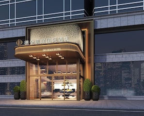 Entrada de hotel con diseño moderno, que presenta un amplio frente de vidrio y un letrero llamativo.