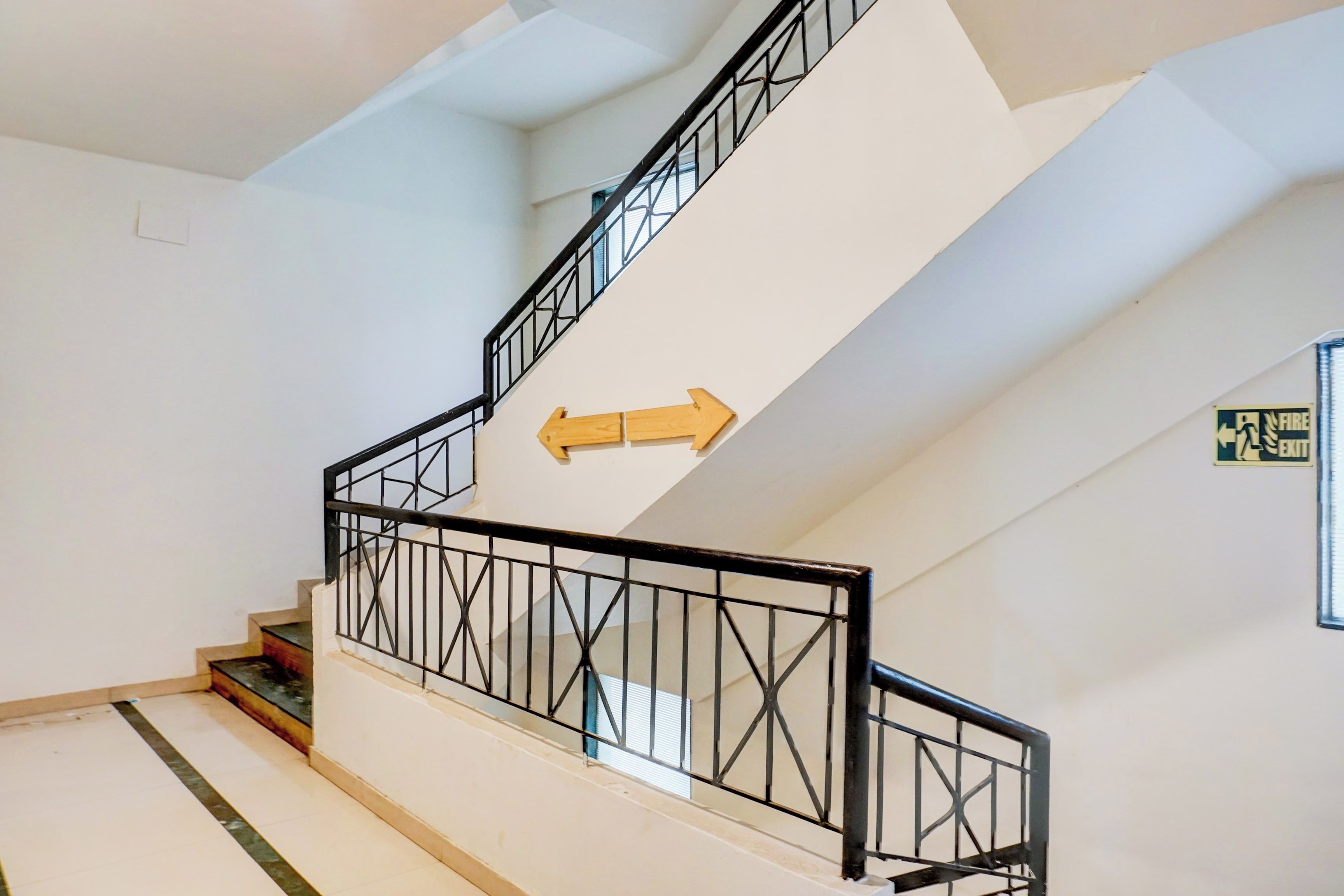 A staircase with black railings and a directional arrow sign.