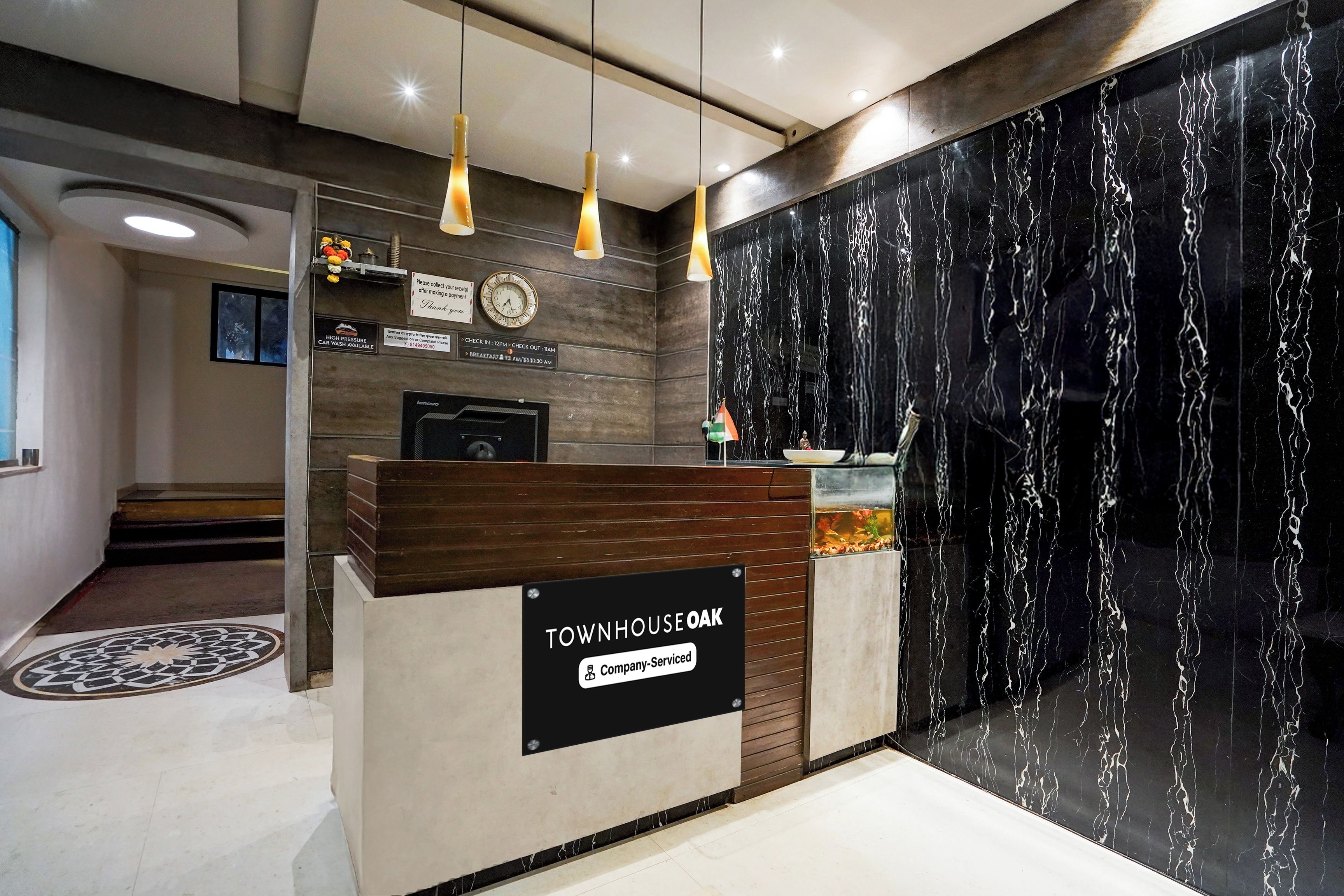 A reception desk with a sign indicating it is a company-serviced location. There is a clock and a car wash availability sign above the desk.