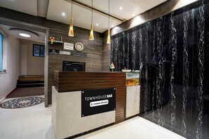 Una recepción con un letrero que indica que es un lugar de servicio de empresa. Hay un reloj y un anuncio de disponibilidad de lavado de autos sobre el mostrador.