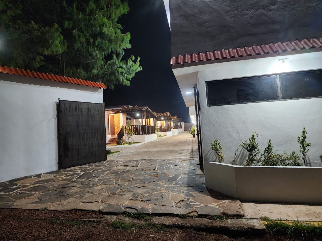 A paved pathway leading to a building with a tiled roof and a dark door.