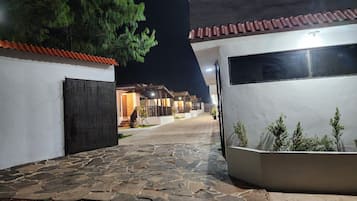 A paved pathway leading to a building with a tiled roof and a dark door.