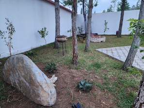A garden with a large rock, small plants, a wooden bench, and a table.