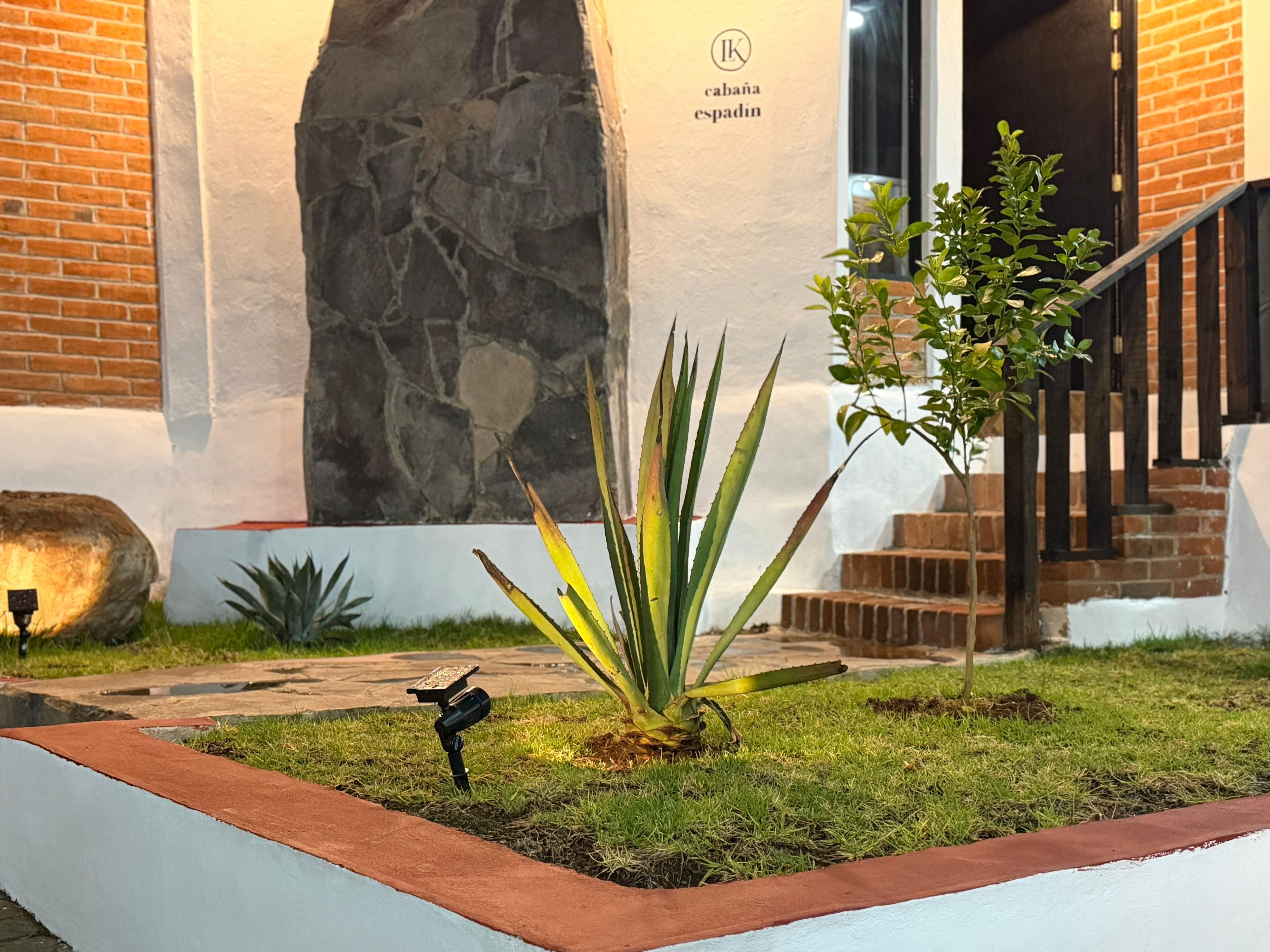 A landscaped garden area with a stone wall, a staircase, and a small tree.