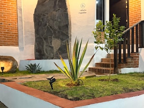 A landscaped garden area with a stone wall, a staircase, and a small tree.