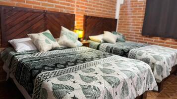A room with two beds, each with patterned bedding and a brick wall.