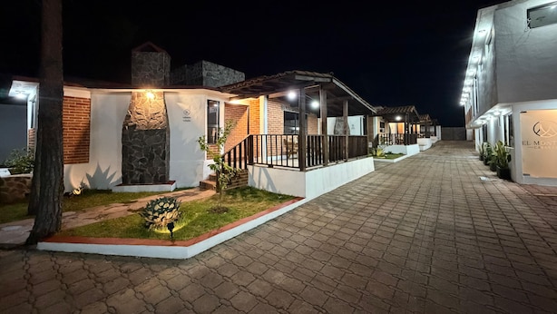 Una hilera de edificios modernos, bien iluminados, con fachadas de piedra y detalles de madera, sugiriendo un entorno de hotel o resort contemporáneo.