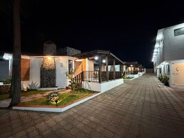 A row of modern, well-lit buildings with stone facades and wooden accents, suggesting a contemporary hotel or resort setting.