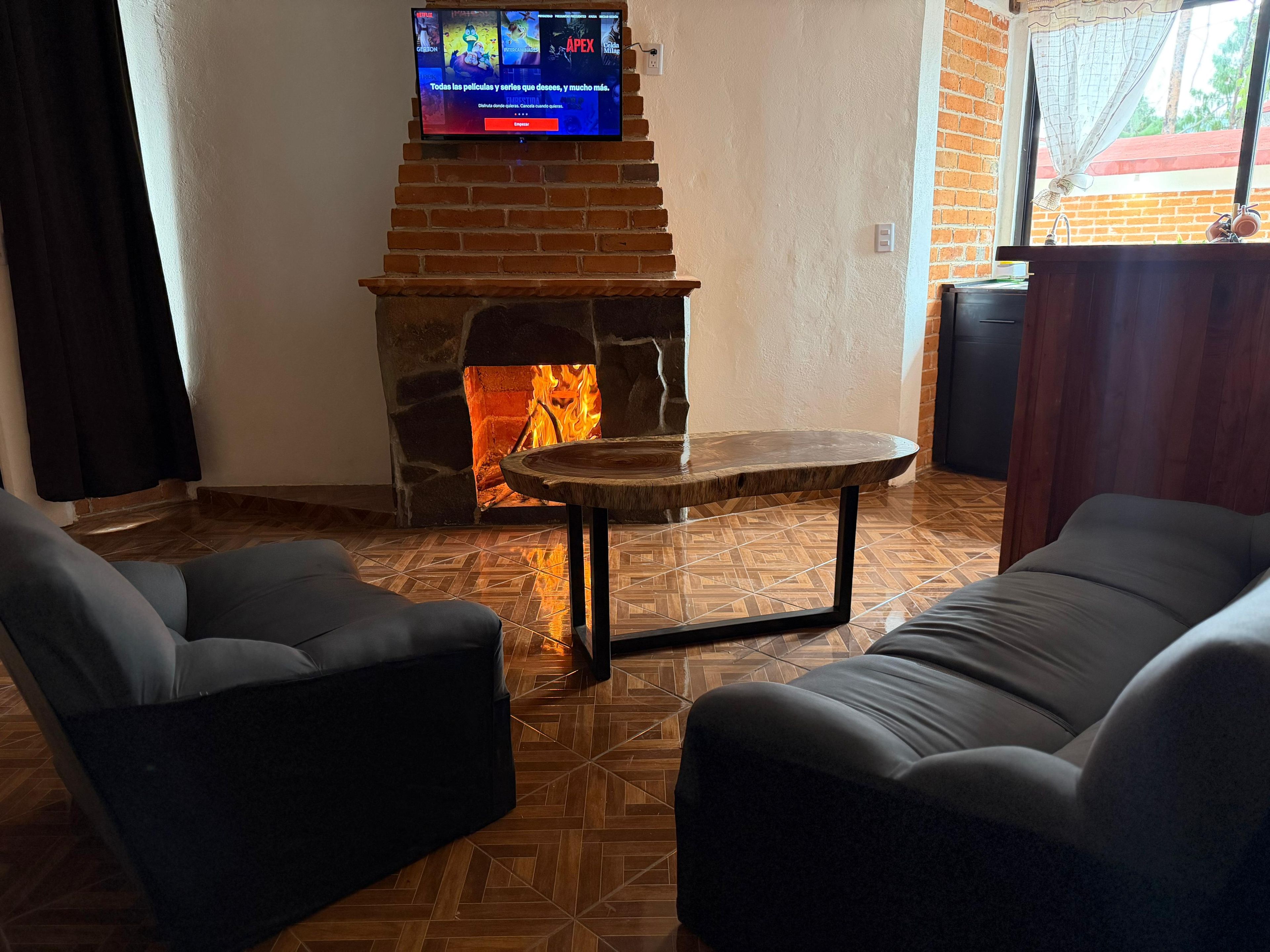 A living room with a stone fireplace, a television mounted above it, and two sofas.