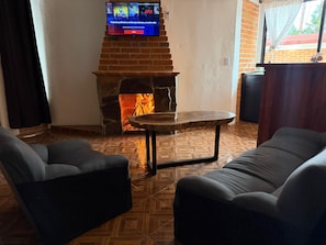 A living room with a stone fireplace, a television mounted above it, and two sofas.