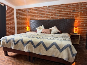 Una cama con una colcha estampada, un cabecero de madera y dos lámparas de noche con motivos florales.