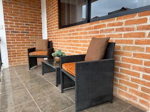A patio area with wicker furniture and a potted plant.