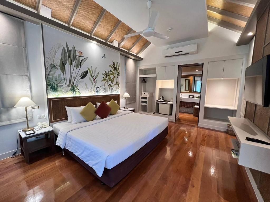 Amplia habitación de hotel con una cama grande, ventilador de techo, televisor de pared y escritorio integrado.