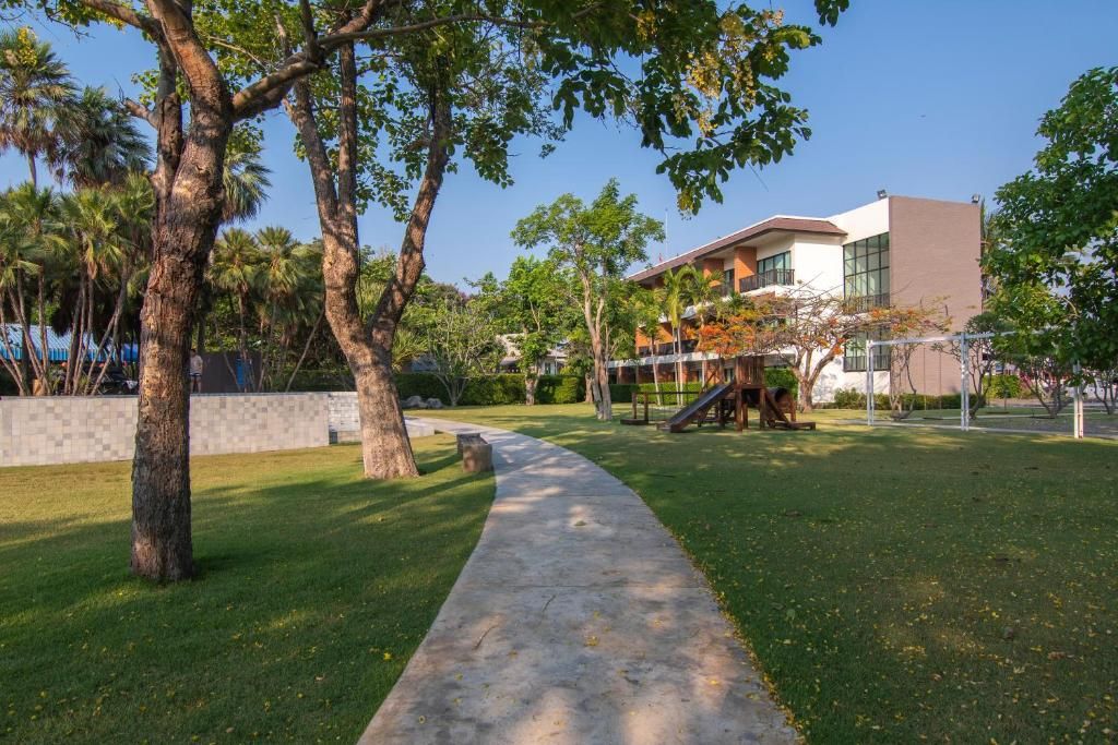 A pathway leading to a building with a modern design, surrounded by trees and a well-maintained lawn.