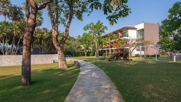 A pathway leading to a building with a modern design, surrounded by trees and a well-maintained lawn.