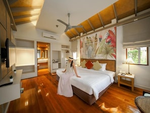 Een ruime slaapkamer met een groot bed, een plafondventilator en een muurschildering.