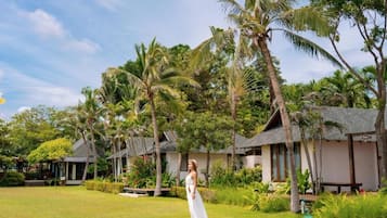 A tropical resort with overwater bungalows, lush greenery, and a clear sky.