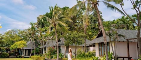 Un resort tropical con bungalows sobre el agua, exuberante vegetación y cielo despejado.