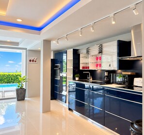A modern kitchen with a large island, stainless steel appliances, and a view of a swimming pool. - 5 bedroom & bathroom, Golf view villa, near Patong. Peacful & private. (Tambon Kathu)